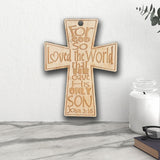 Wood Engraved Cross with John 3:16 quote  and hole on top for hanging shown against a wall near a counter