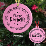 Nurse Adjectives in a circle such as compassionate, smart, loyal, strong, caring, healing, and hope with any name in the center pictured on a porcelain and plastic ornament.