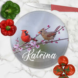 personalized cutting board with a pair of cardinals on a spring flower branch  mocked up on a counter with utensil and vegtables