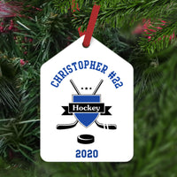 Hockey Crest with cross sticks and puck personalized with name and number arched on top and year on the bottom White ornament with blue and black  image