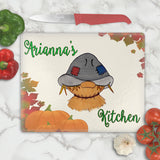exclusive scarecrow from artist print on a glass cutting board with fall leaves and pumpkins